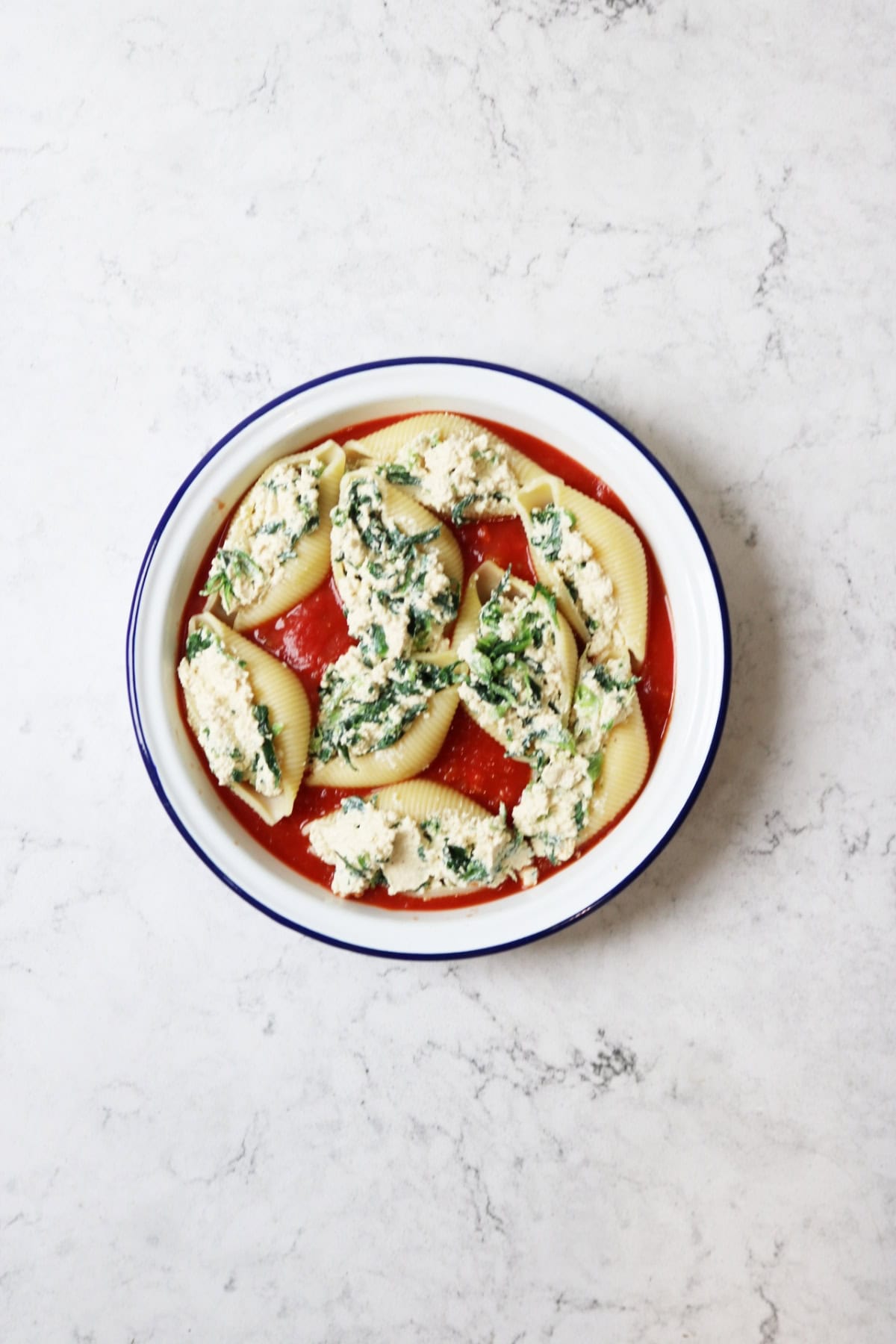 Pasta shells stuffed with vegan spinach and ricotta in an oven dish ready for baking