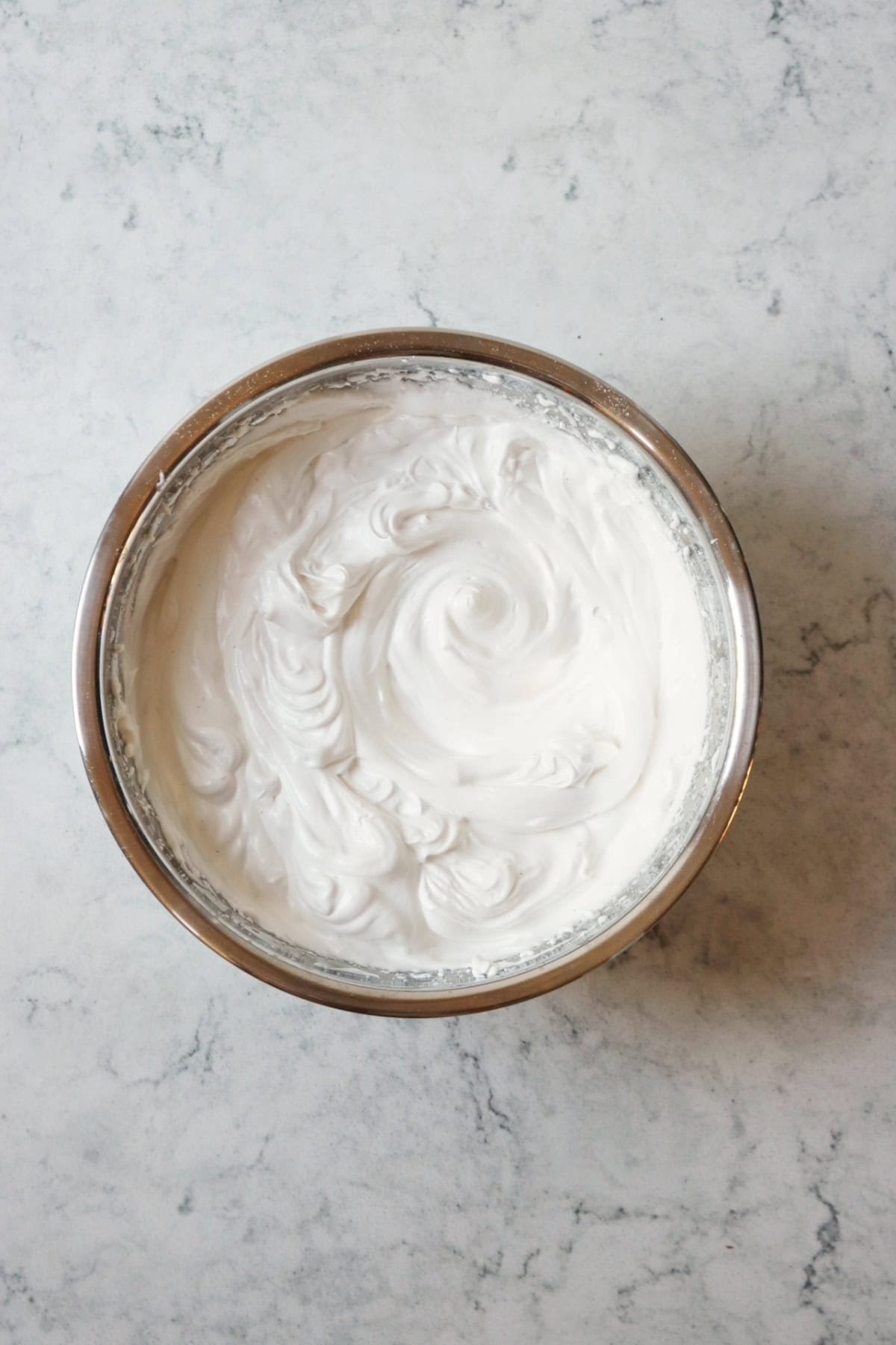Uncooked vegan meringue with vanilla paste in a meta mixing bowl