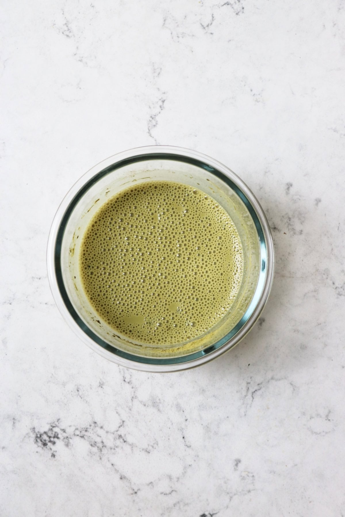 Matcha mixed with plant milk in a glass bowl