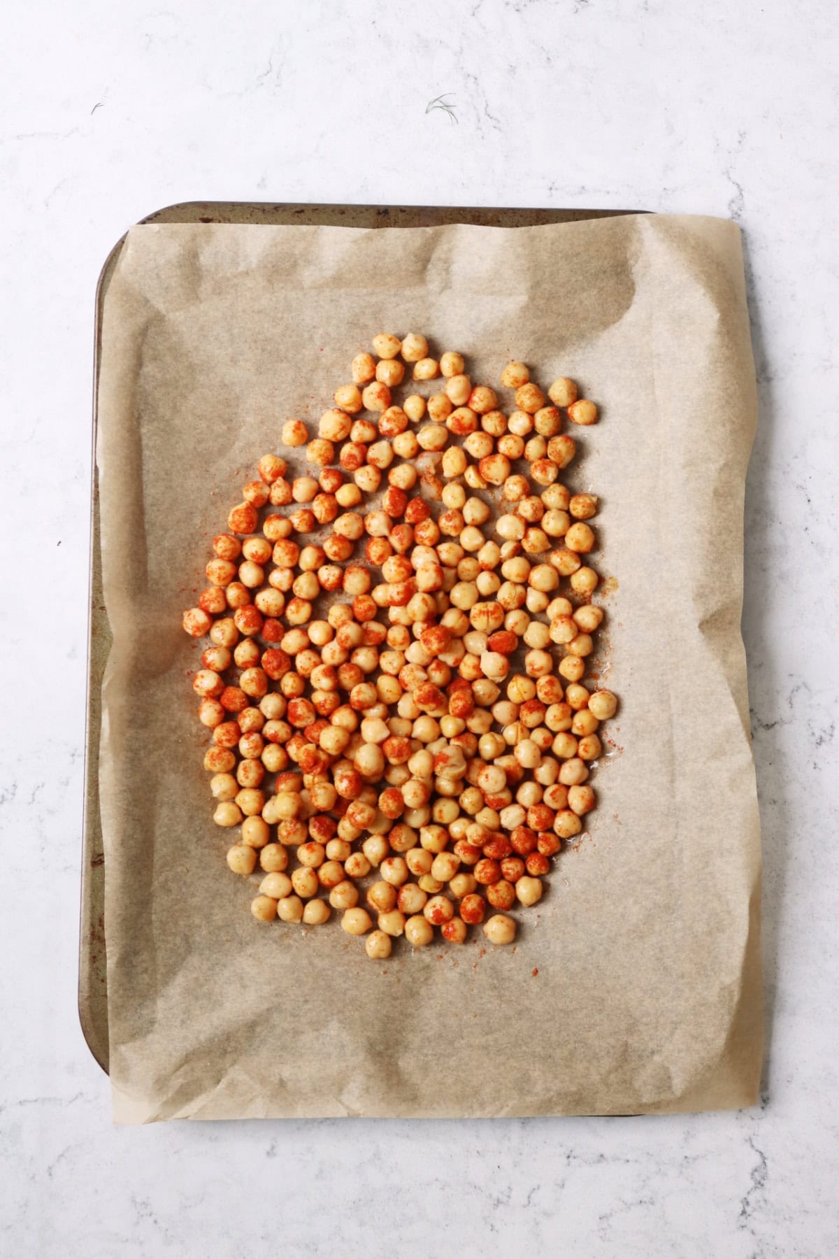 Chickpeas coated in cumin and paprika on a baking tray