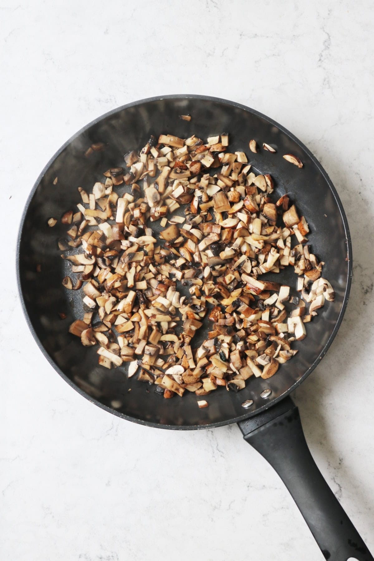 Chopped mushrooms cooking in a frying pan