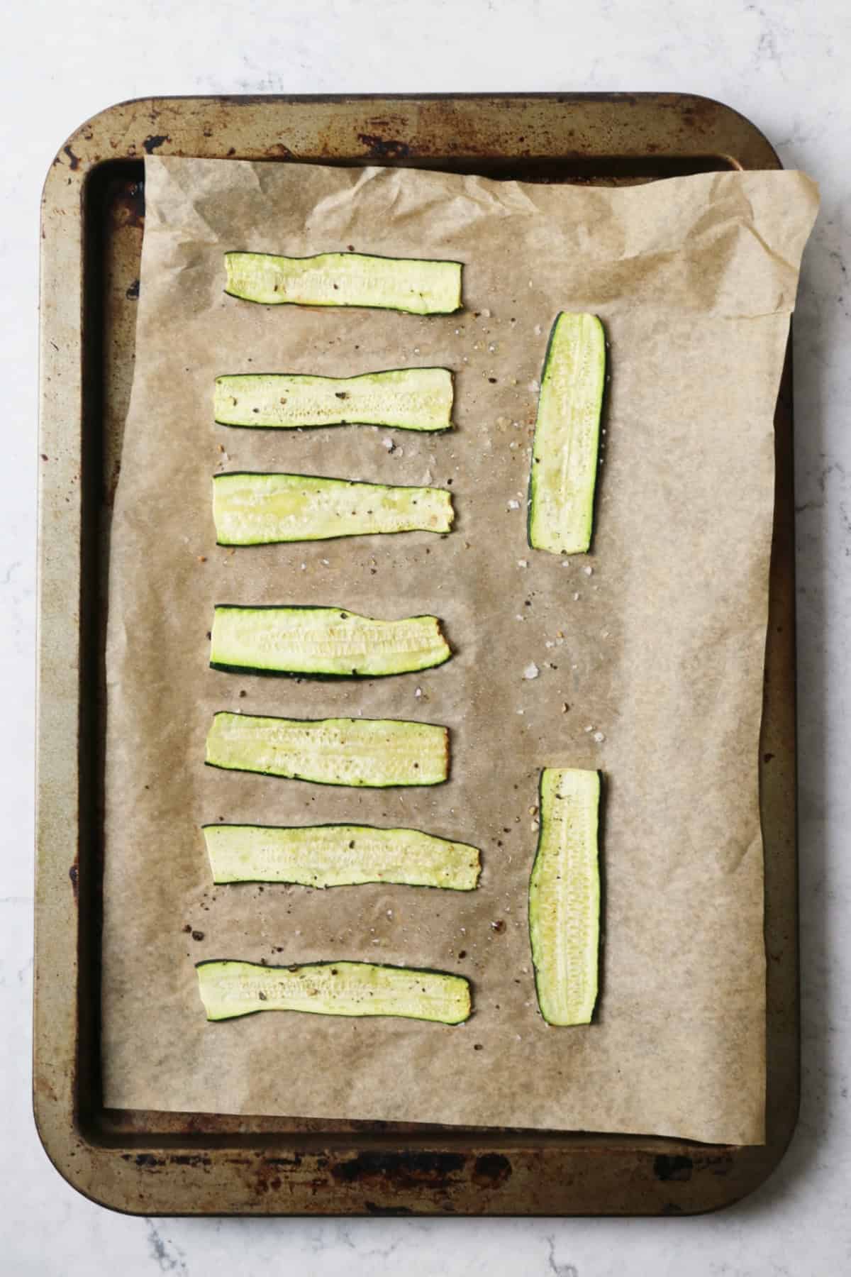 Cooked strips of courgette laid out on a baking tray