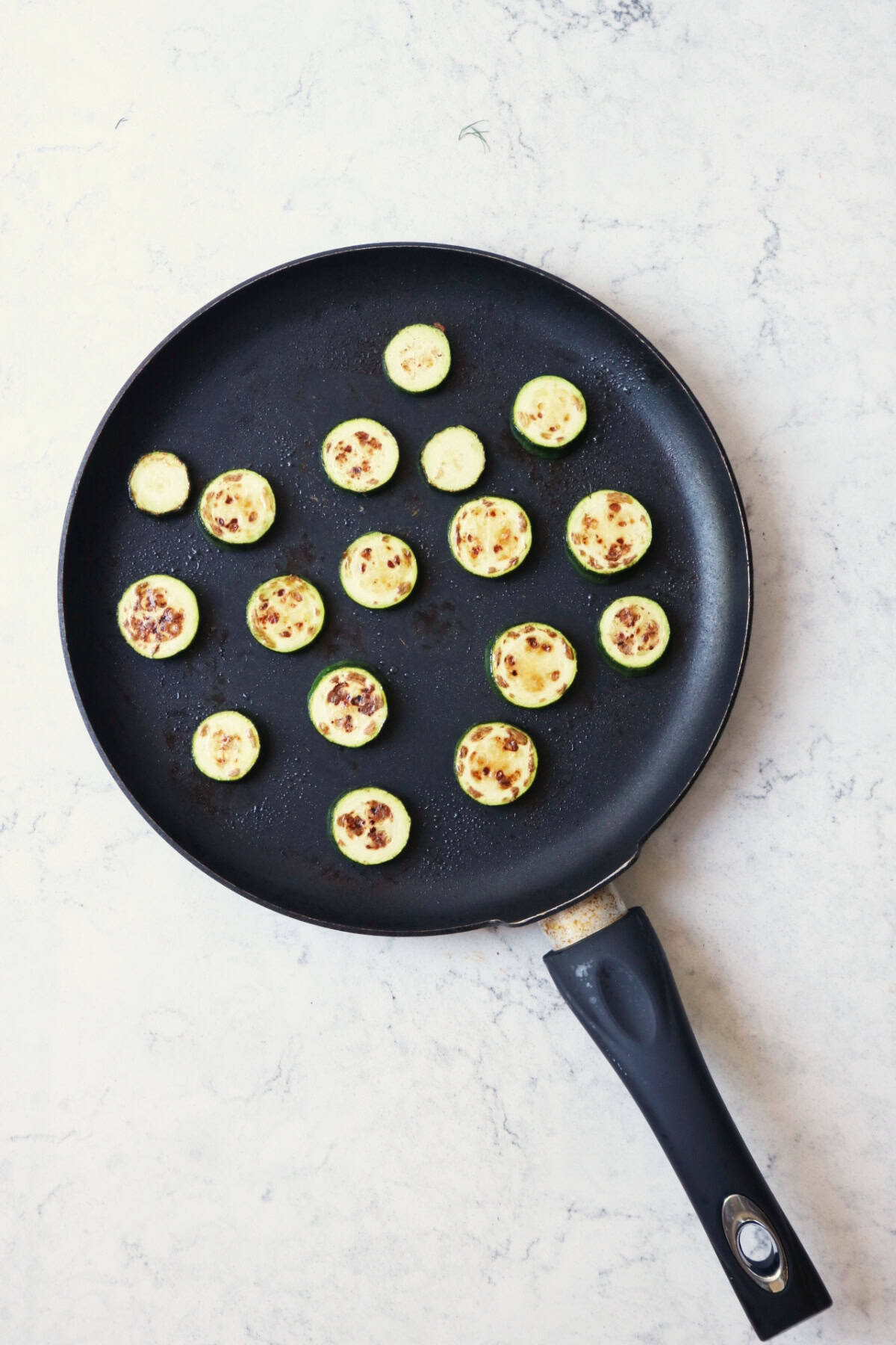 Slices of baby courgette frying in a pan