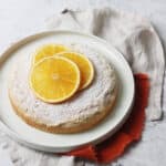 Vegan Orange Polenta Cake dusted with icing sugar and topped with orange slices