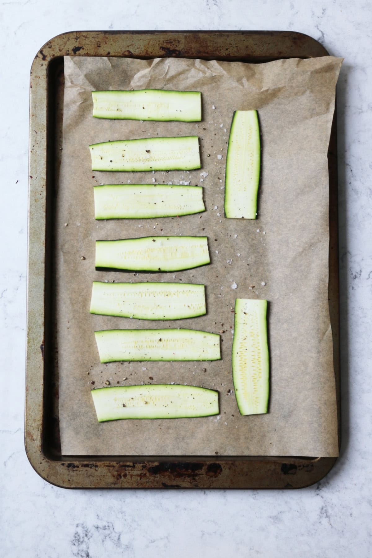 Strips of courgette laid out on a baking tray ready to be cooked in the oven