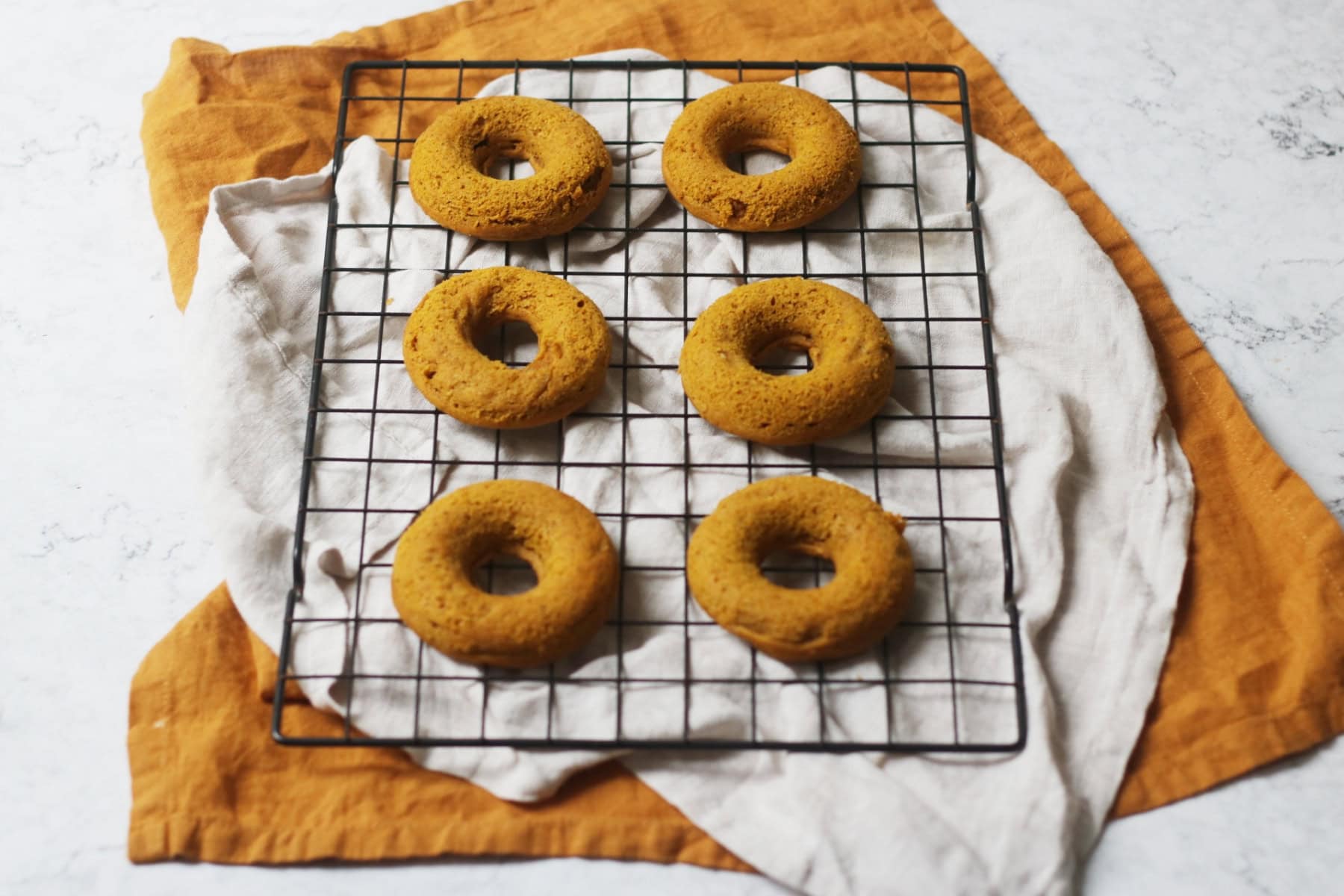 Vegan Baked Pumpkin Spice Doughnuts cooling on a wire rack