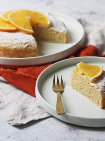 A slice of Vegan Orange Polenta Cake served on a plate with a gold cake fork
