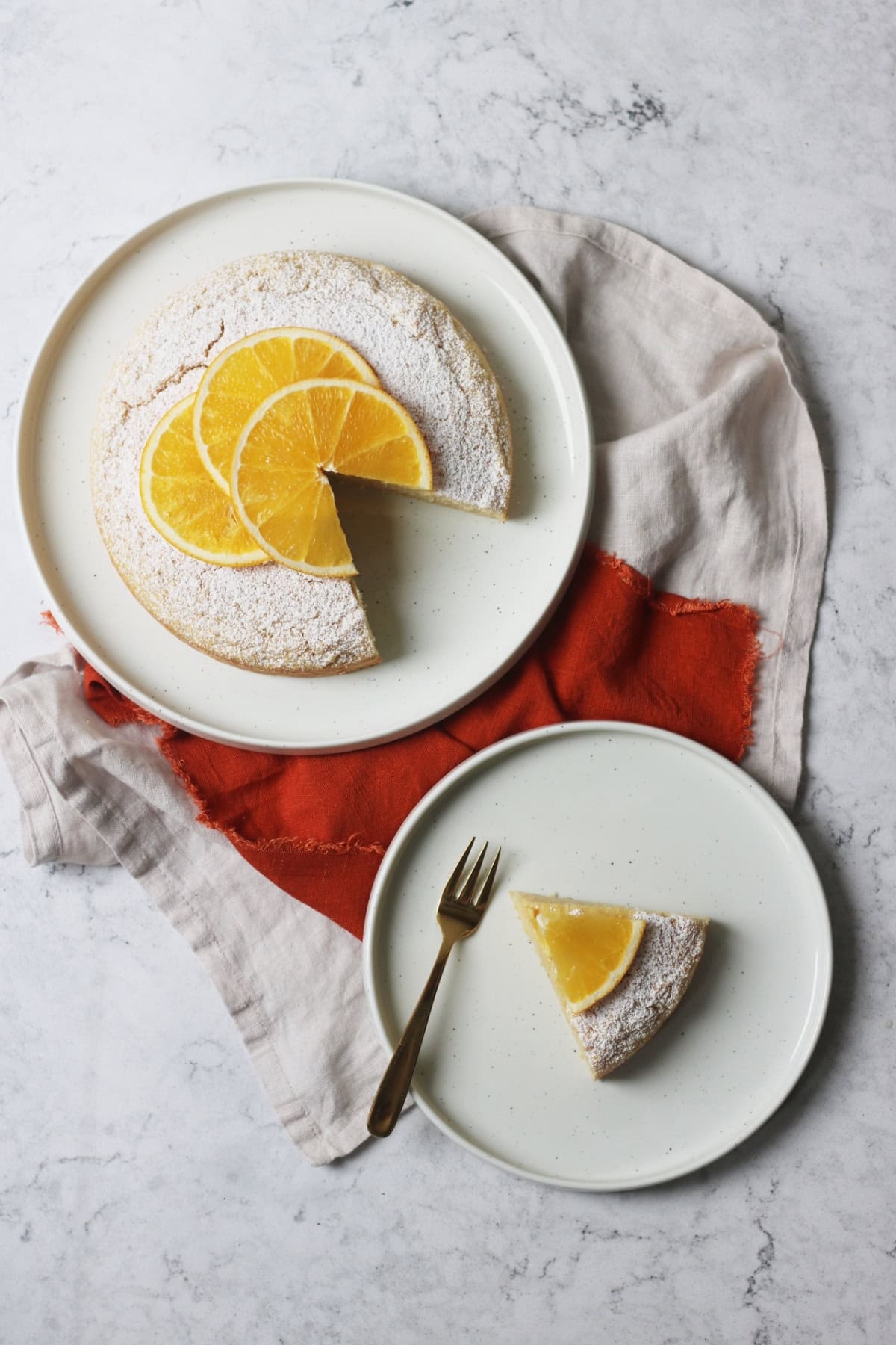 A slice of Vegan Orange Polenta Cake served on a plate with a gold cake fork