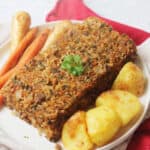 Vegan Savoury Loaf served on a plate with roast potatoes, carrots and parsnips