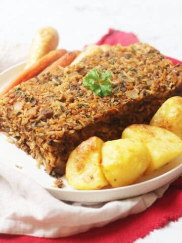Vegan Savoury Loaf served on a plate with roast potatoes, carrots and parsnips