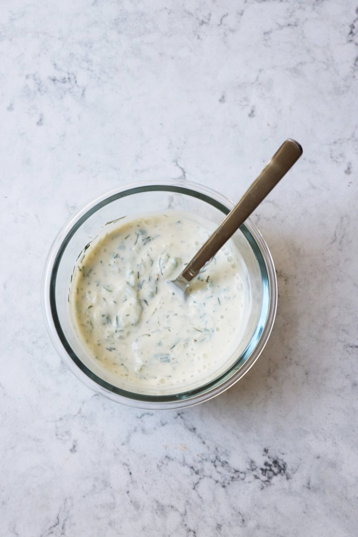 Vegan Tzatziki in a glass bowl with a metal spoon