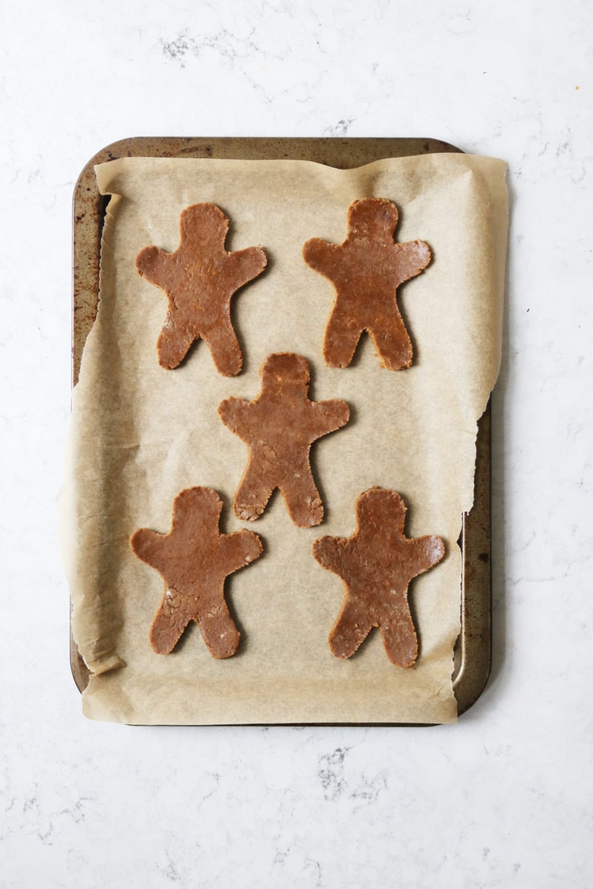Cut out gingerbread men on a baking tray ready for the oven