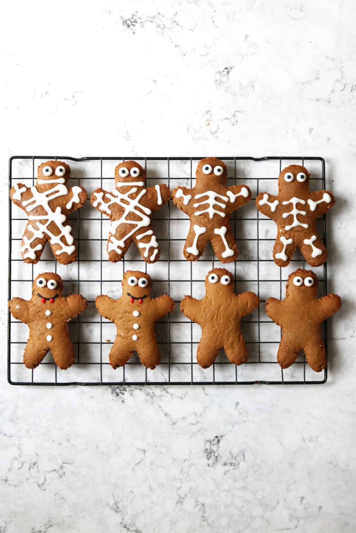 Gingerbread men on a wire rack decorated as mummies, skeletons and vampires