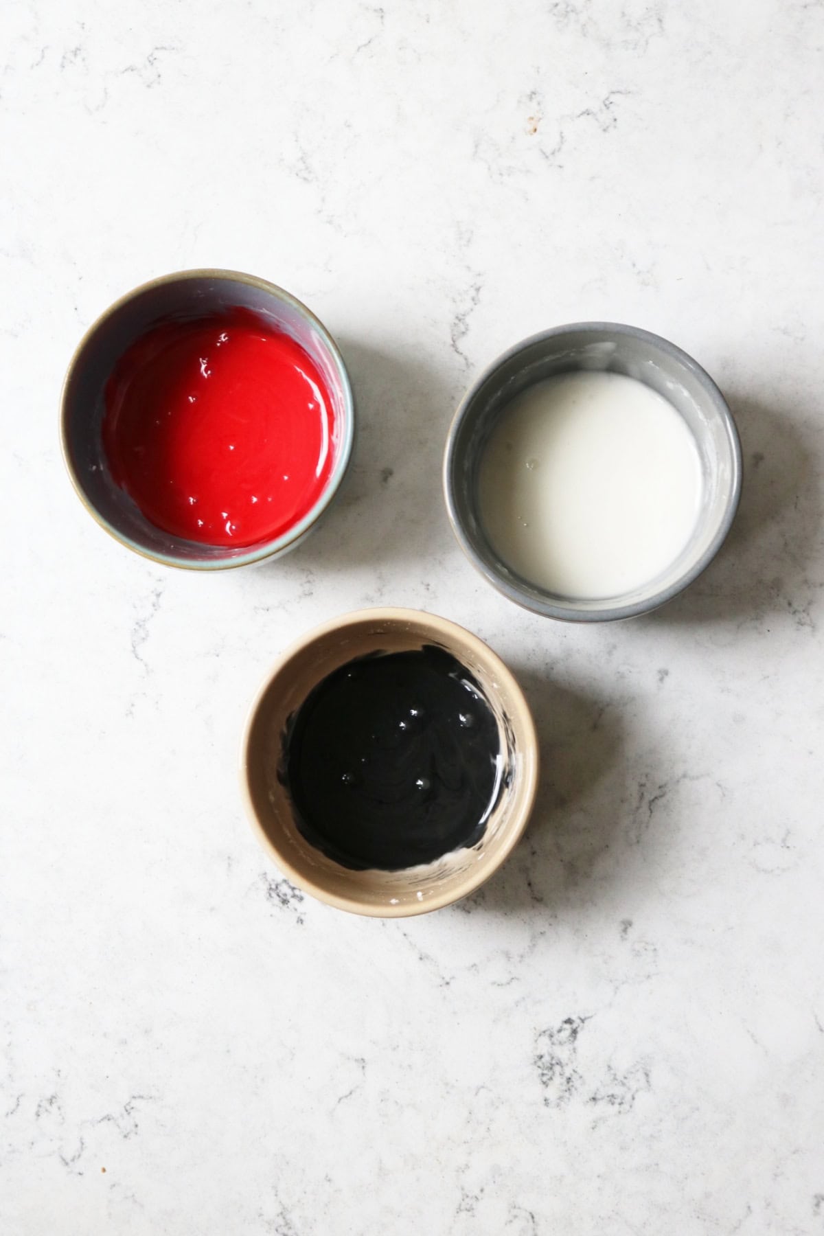 3 bowls filled with red, white and black icing