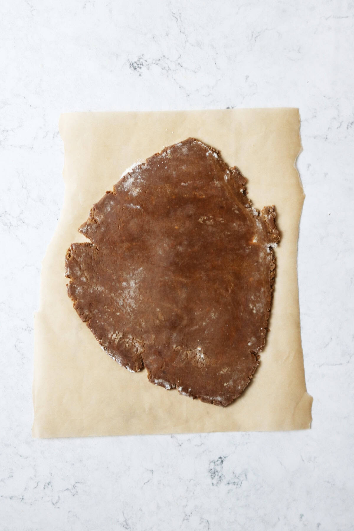 Gingerbread dough rolled out on to a piece of baking paper