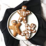 3 gingerbread men decorated as a mummy, skeleton and vampire on a white plate