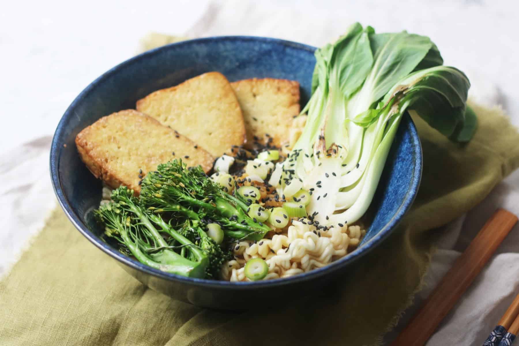 A bowl of vegan ramen topped with smoked tofu, tenderstem broccoli, spring onions, sesame seeds and pak choi