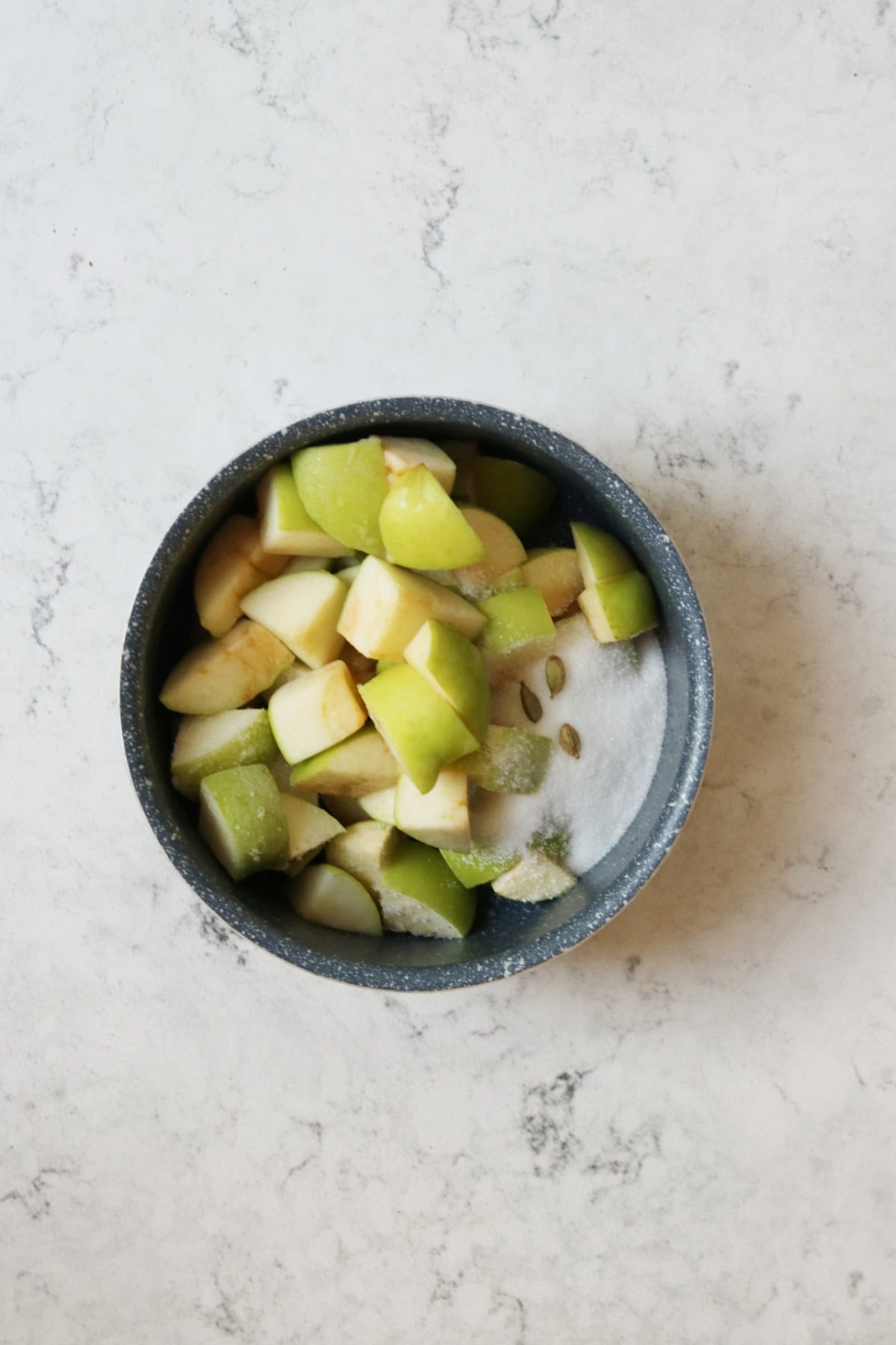 Apples, rose water, caster sugar and cardamom pods cooking in a small saucepan