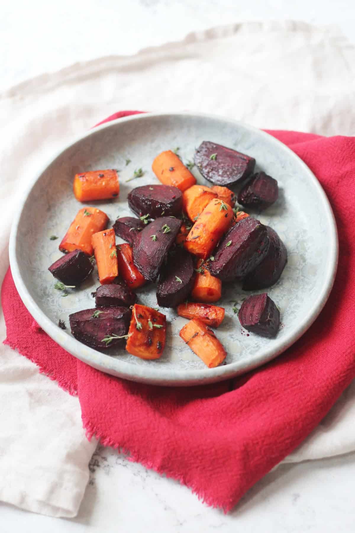Roasted Beetroot and Carrots with Balsamic and topped with thyme on a blue plate