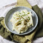 Vegan Garlicky Mashed Potatoes topped with Chives on a blue plate