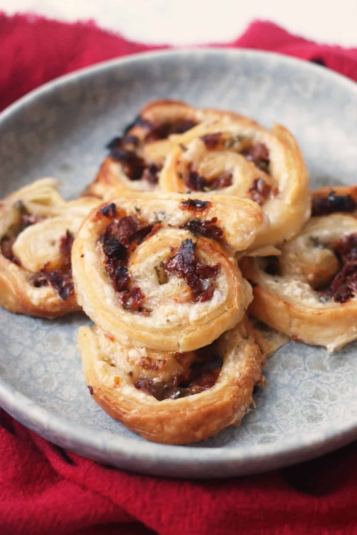 A plate of Vegan Sun-Dried Tomato and Feta Pinwheels on a red napkin