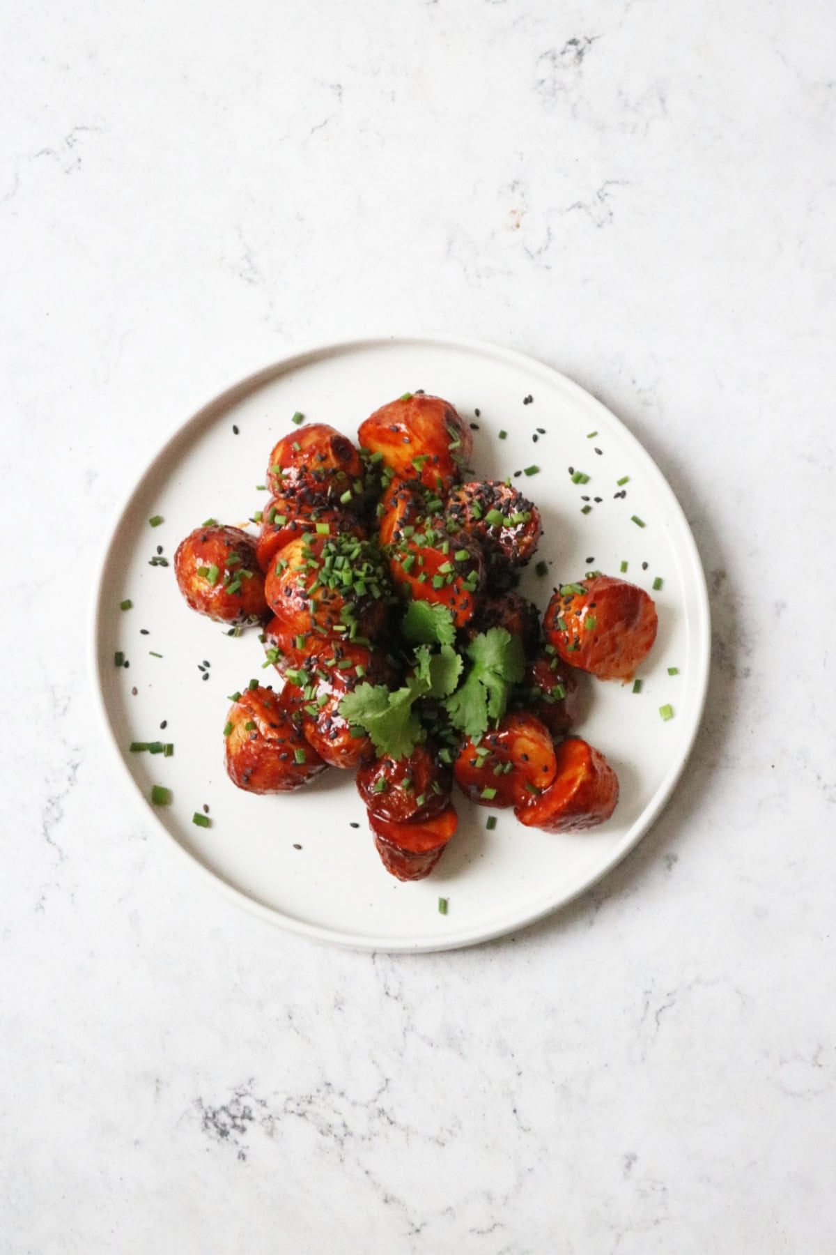Crispy Gochujang Potatoes garnished with sesame seeds, chives and coriander