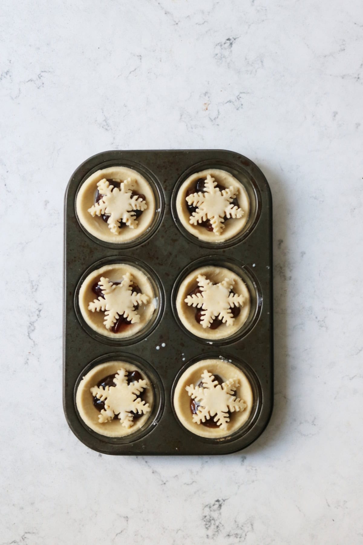 Mince pies in a muffin tin ready for the oven