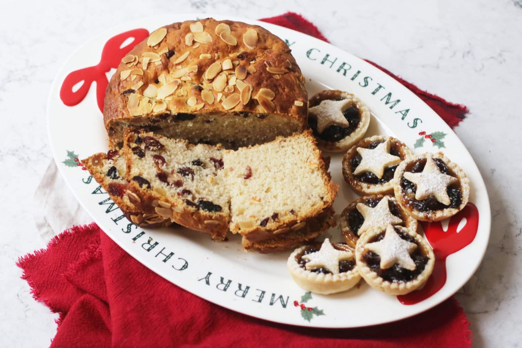 Slices of vegan panettone and vegan mince pies served on a Christmas platter
