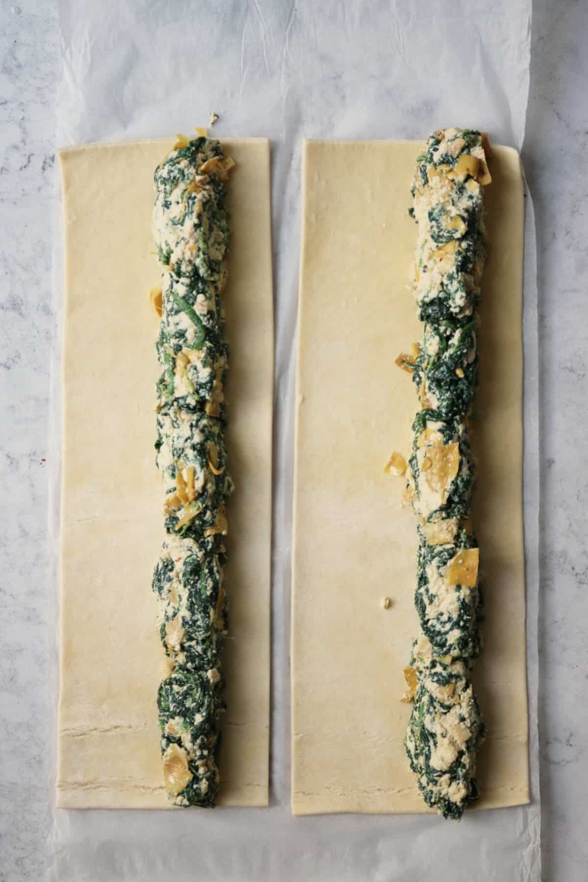 Two long rectangles of pastry with spinach and artichoke filling