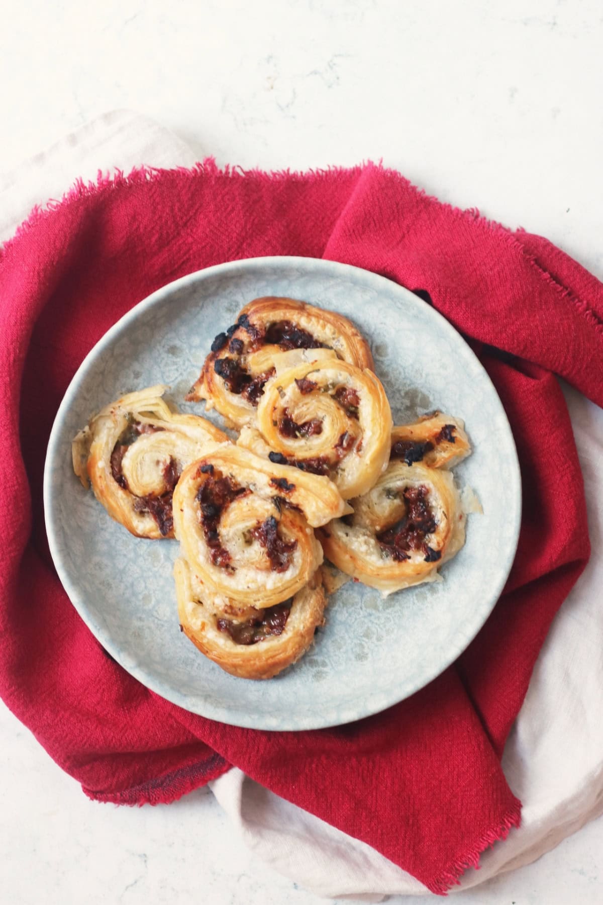 A plate of Vegan Sun-Dried Tomato and Feta Pinwheels on a red napkin