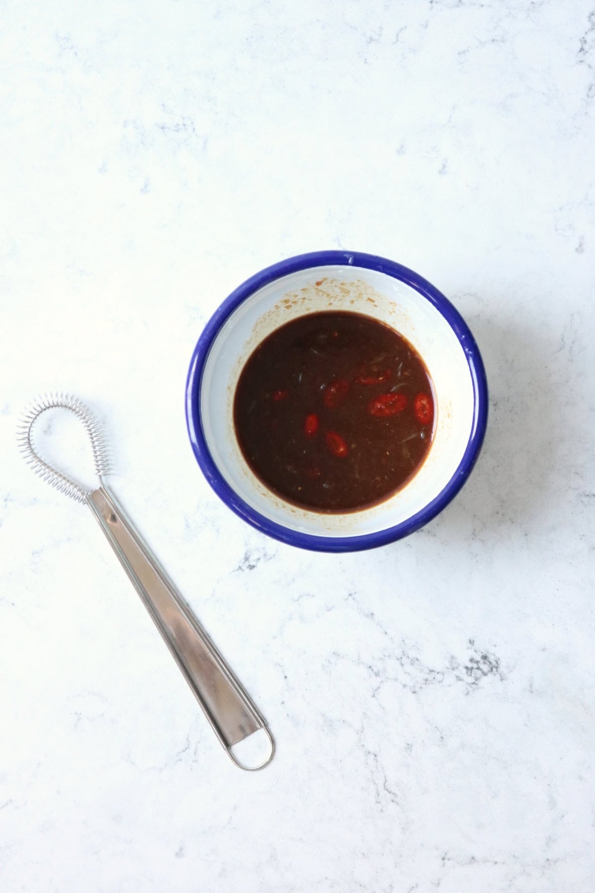 Soy and ginger glaze and dressing in an enamel bowl with a blue rim
