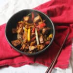 Sweet and Spicy Tempeh Stir Fry with red and yellow peppers in a black bowl
