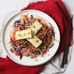 Tea Smoked Tofu with Rice Noodle Salad served on a white plate with wooden chopsticks on a red napkin