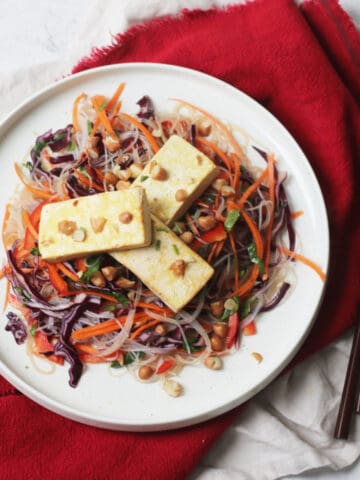 Tea Smoked Tofu with Rice Noodle Salad served on a white plate with wooden chopsticks on a red napkin
