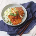 A plate of soy glazed tofu served on top of white rice and peas