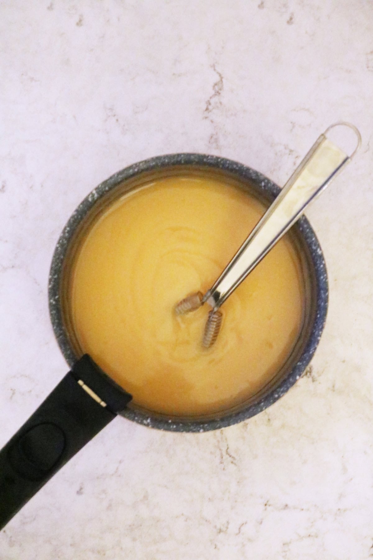 Whisking plant milk and vegan butter into blood orange curd until smooth and thick