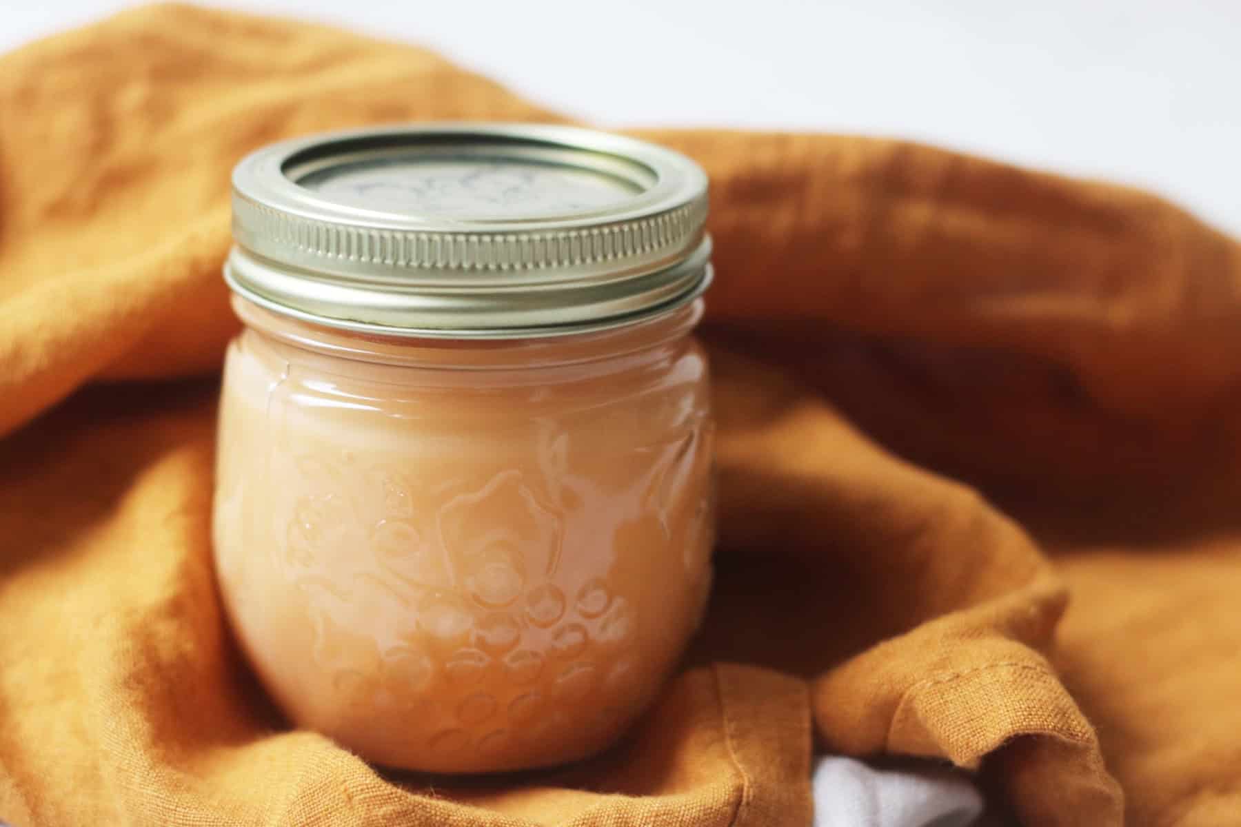 A jar of vegan blood orange curd nestled in an orange napkin