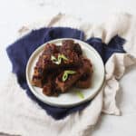 Vegan Chinese Spare Ribs stacked high on a plate with a dark blue napkin