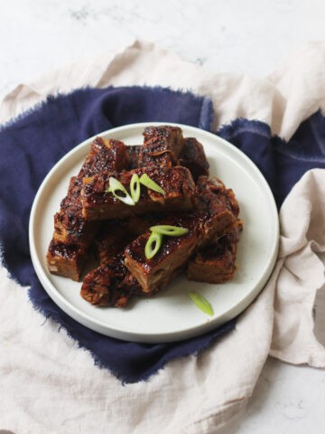 Vegan Chinese Spare Ribs stacked high on a plate with a dark blue napkin
