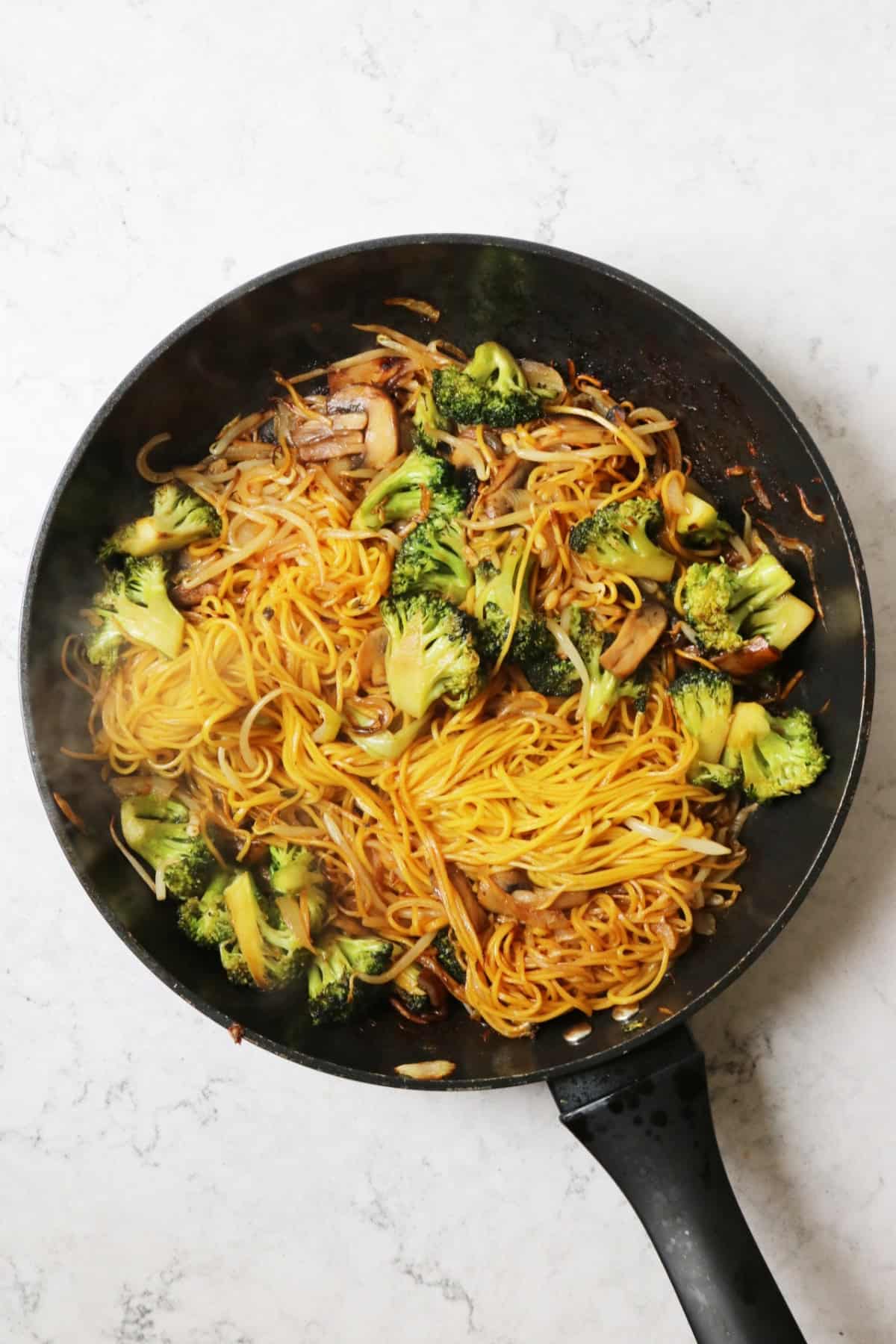 Vegan Broccoli and Mushroom Chow Mein cooking in a large frying pan