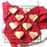 Vegan Heart Shaped Strawberry Cookies cooling on a wire rack on top of a red napkin