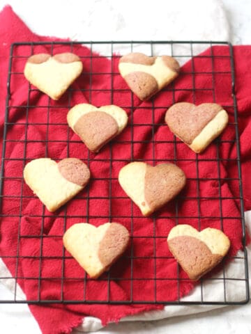 Vegan Heart Shaped Strawberry Cookies cooling on a wire rack on top of a red napkin
