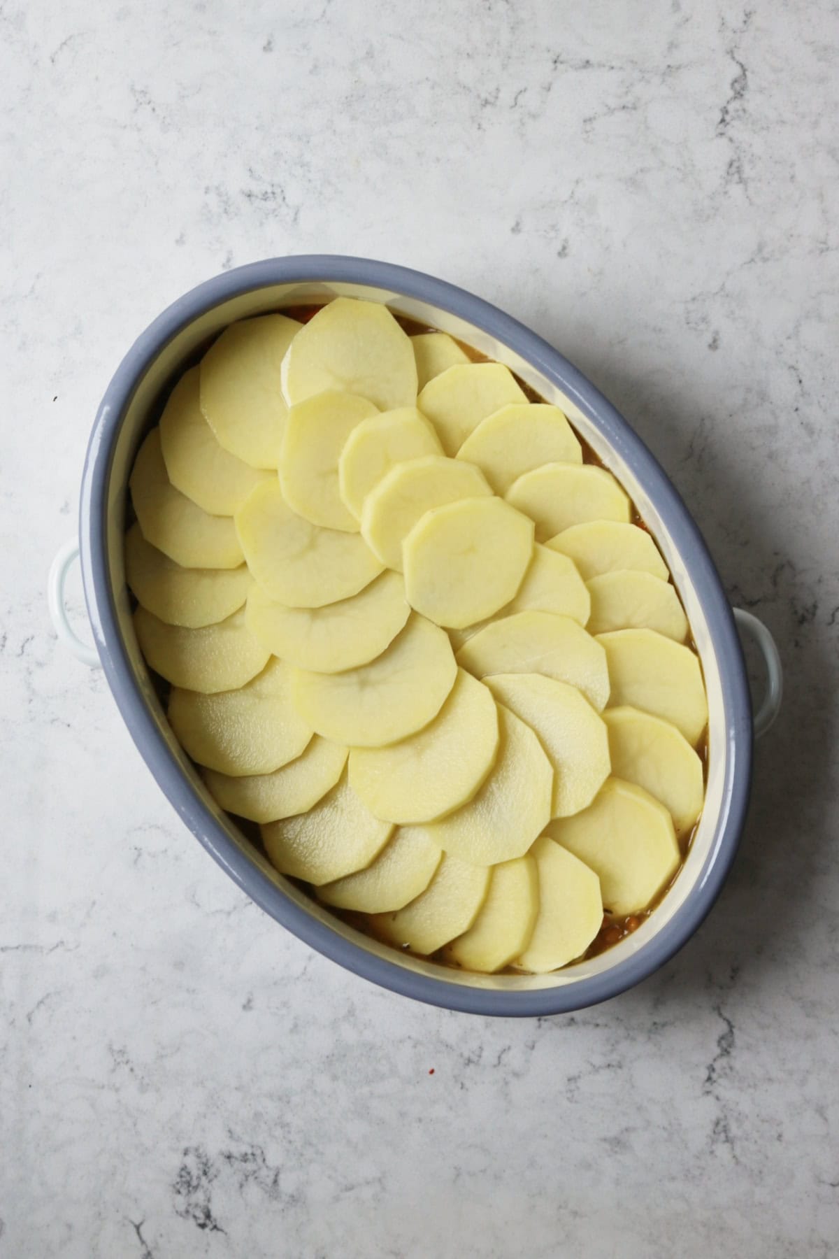 An oven dish filled with Vegan Lancashire Pot yet to be cooked in the oven