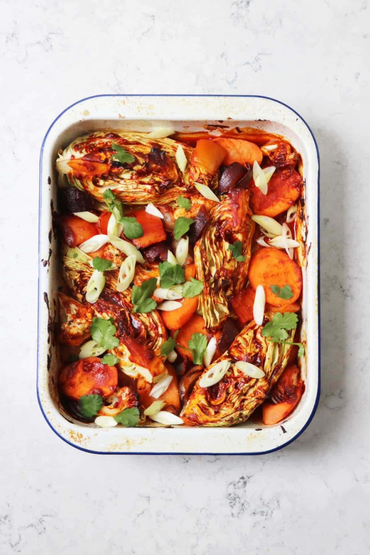 Crispy Vegan Gochujang Vegetable Traybake topped with sliced spring onions and coriander leaves