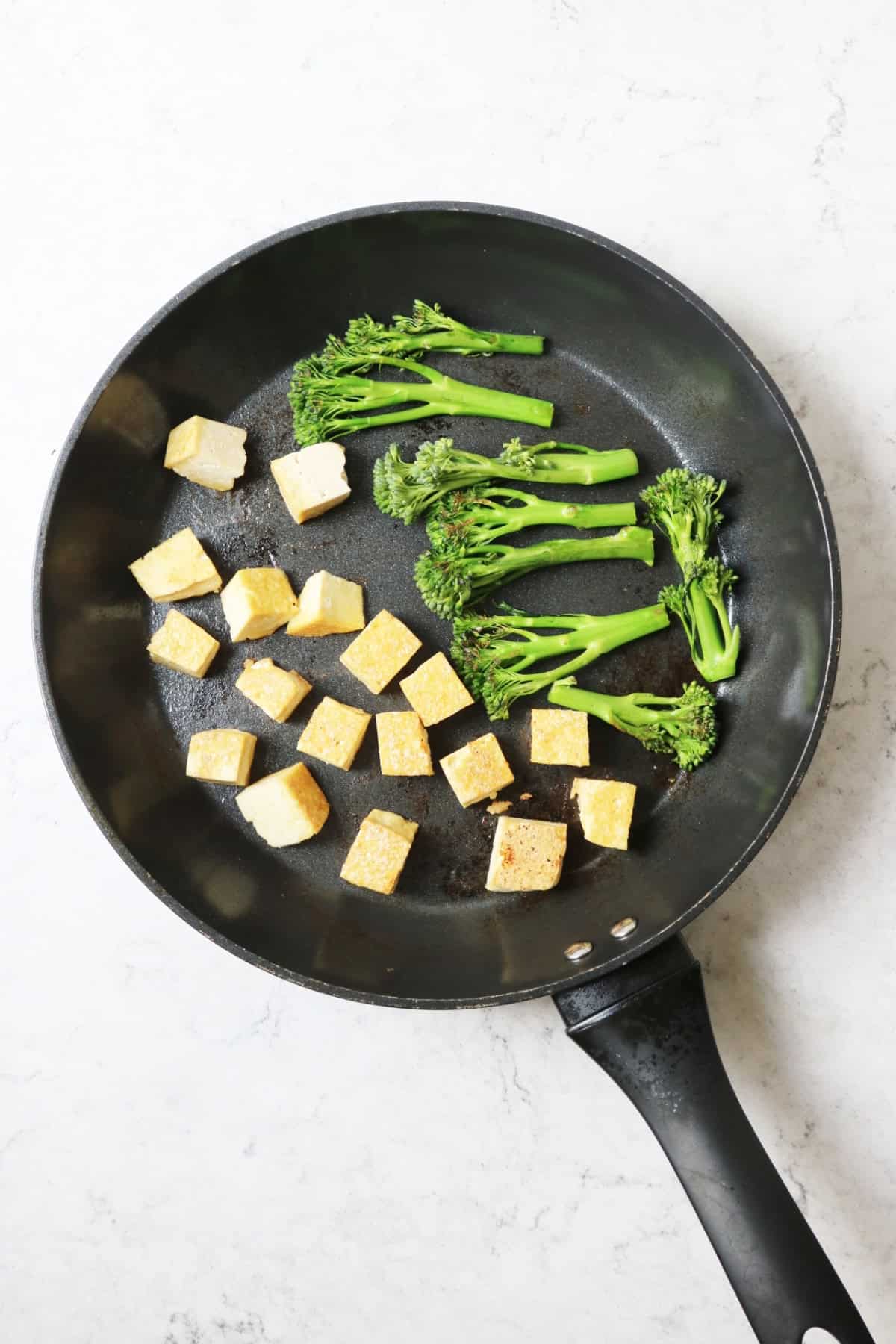 Frying tofu and Tenderstem broccoli in a large bottomed saucepan for Vegan Thai Red Curry Noodle Soup