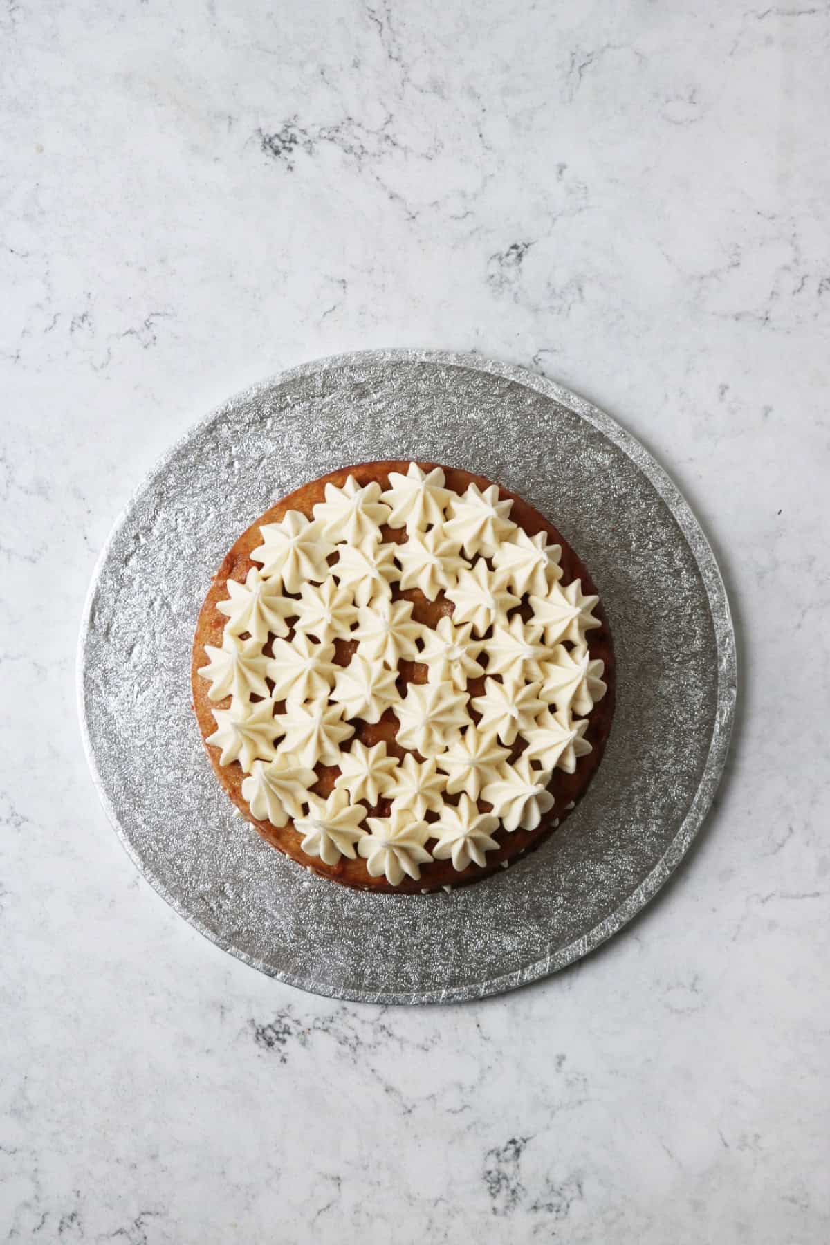 Vegan cream cheese frosting piped on top of layers of vegan banana cake