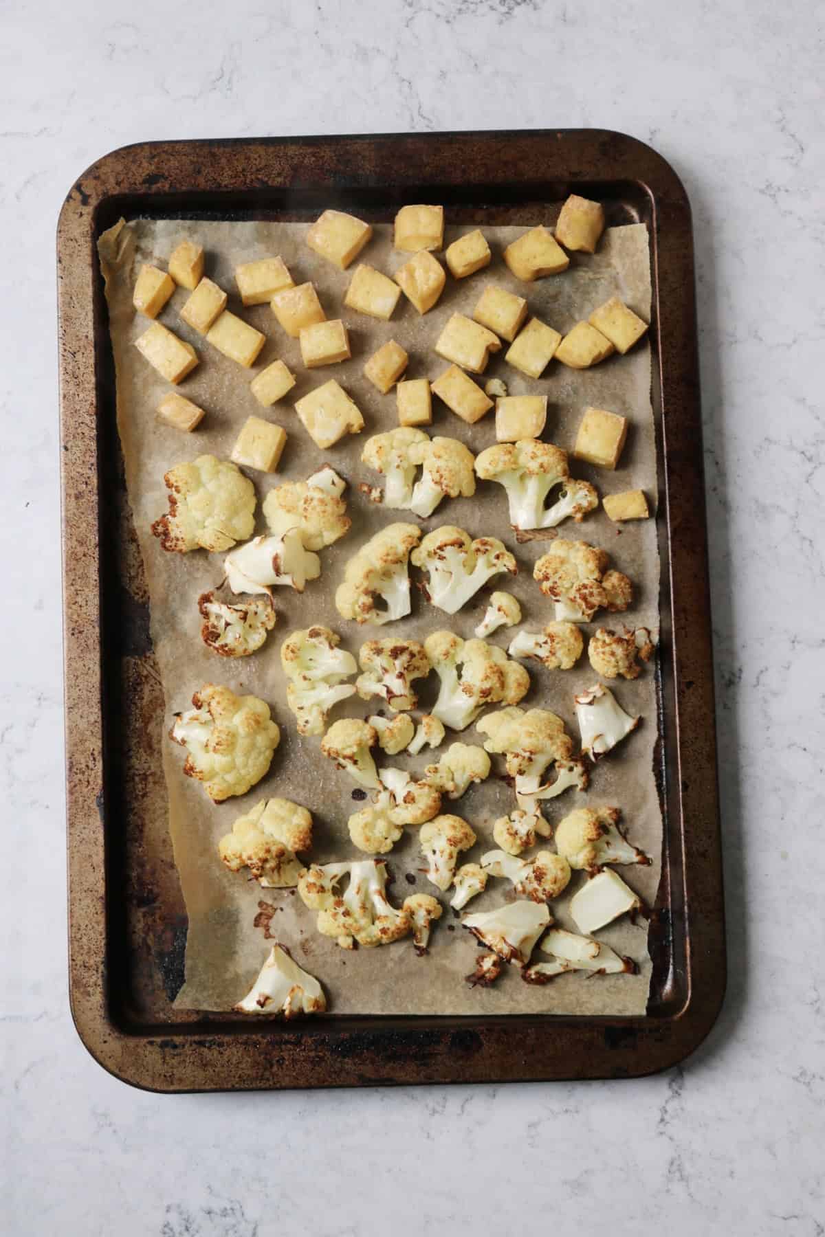 A baking tray of roasted cauliflower and cubes of tofu
