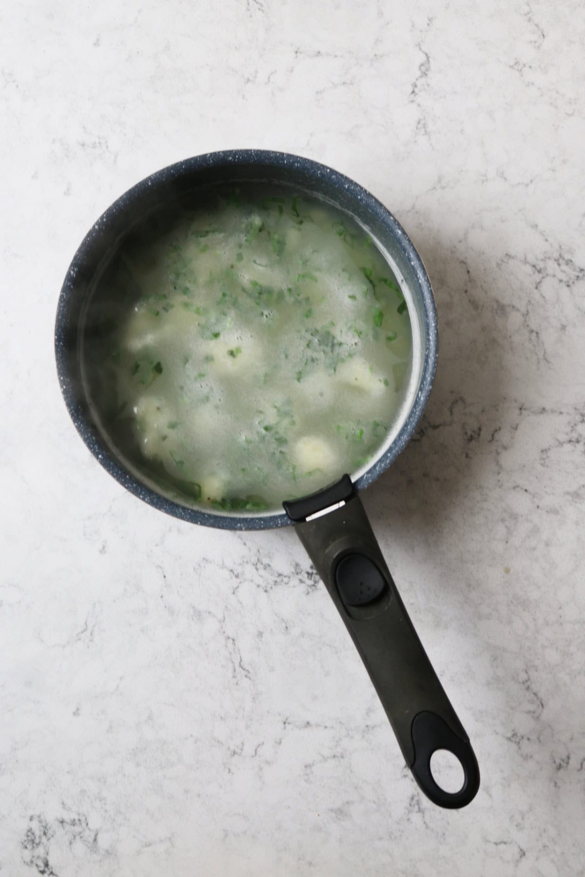 Vegan wild garlic gnocchi simmering in a pan of hot water