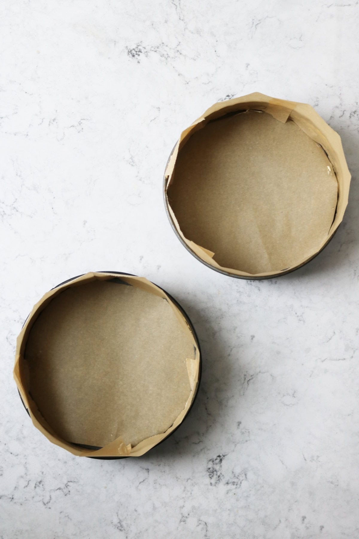 Two 8 inch metal cake tins lined with brown baking paper