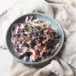 A plate of Vegan Kohlrabi Slaw, topped with chives, served on a light blue plate on top of cream napkins